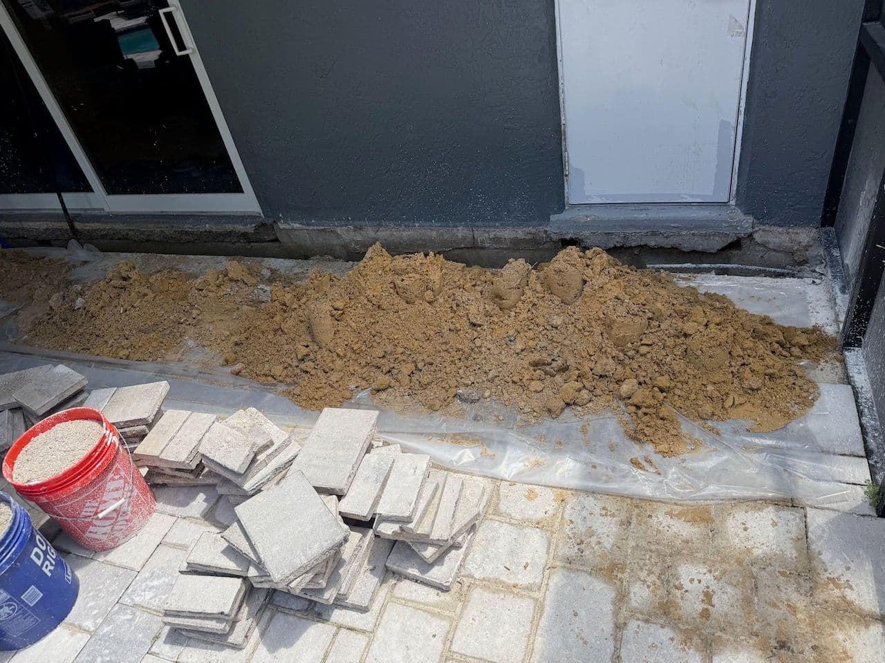Foundation Waterproofing Foundation excavation site at a Florida home with concrete pavers and sand exposed, prepared for waterproofing work