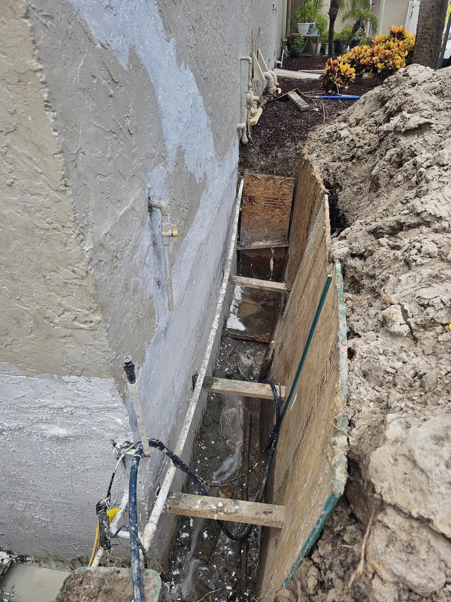 Exterior foundation wall of a Florida home with gray waterproofing membrane applied during excavation and waterproofing installation